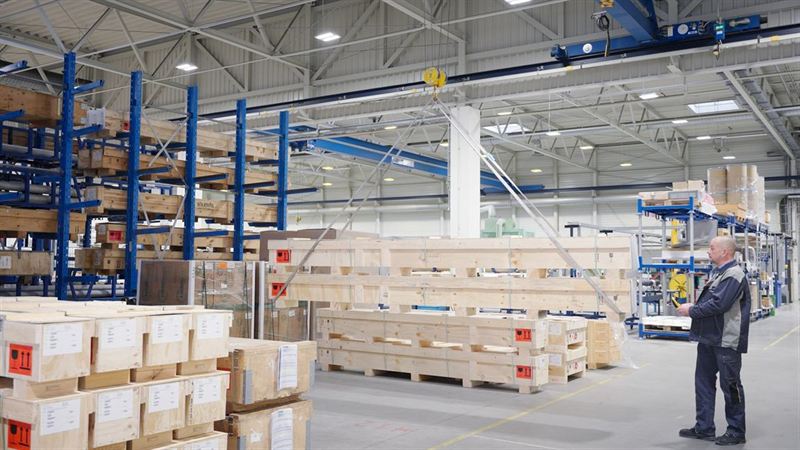 Lagerhalle mit Holzkisten auf Regalen, einem Hallenkran und einem Mitarbeiter bei der Kontrolle – Sicherheitsvideo für GFE Fremat GmbH
