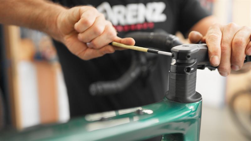Nahaufnahme zweier Hände, die mit einem Werkzeug den Lenkervorbau eines Fahrrads einstellen – Werbefilm für Zweiradhaus Lorenz